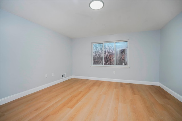 empty room featuring baseboards, visible vents, and wood finished floors