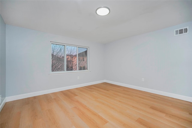 empty room with baseboards, visible vents, and wood finished floors