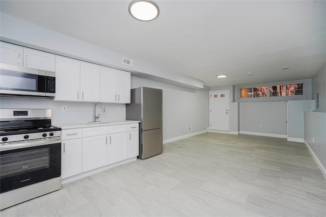 kitchen with light countertops, visible vents, appliances with stainless steel finishes, white cabinets, and a sink