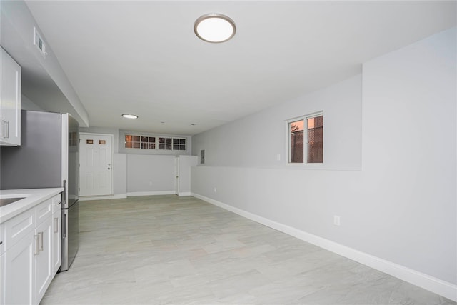 kitchen with visible vents, baseboards, white cabinets, light countertops, and freestanding refrigerator