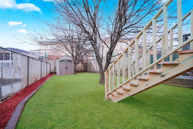 view of yard with a storage shed, a fenced backyard, stairway, and an outbuilding