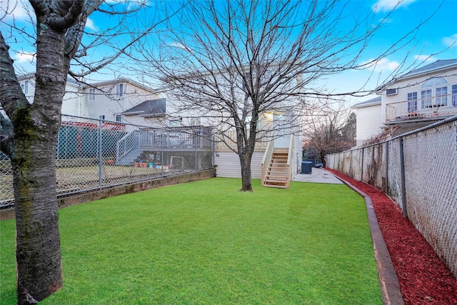 view of yard featuring a fenced backyard and stairs