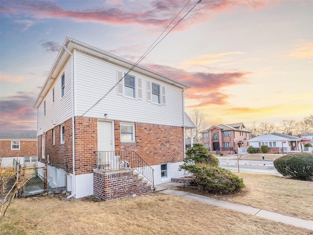 back of property featuring a gate, a lawn, brick siding, and fence