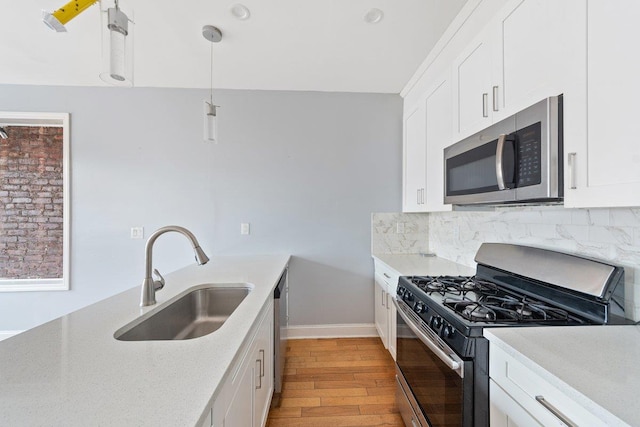 kitchen with stainless steel appliances, a sink, white cabinetry, backsplash, and light wood finished floors