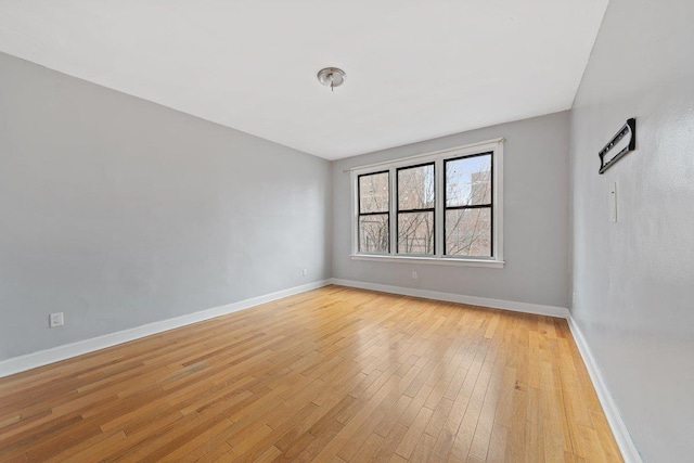 spare room featuring light wood-style floors and baseboards