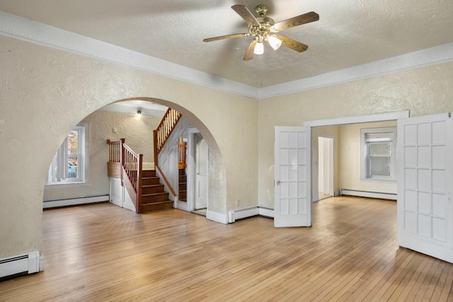 interior space featuring arched walkways, a textured wall, baseboard heating, and wood-type flooring