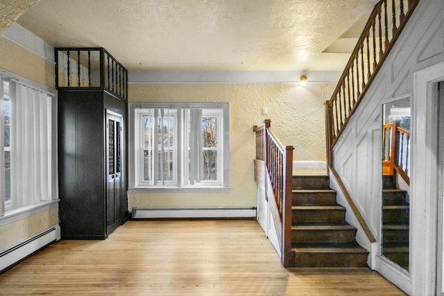 entrance foyer with a textured ceiling, baseboard heating, wood finished floors, and a textured wall