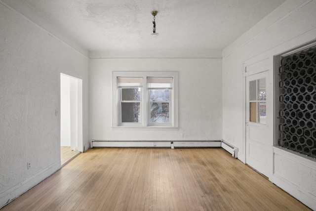 spare room with light wood finished floors, baseboard heating, a textured ceiling, and a textured wall