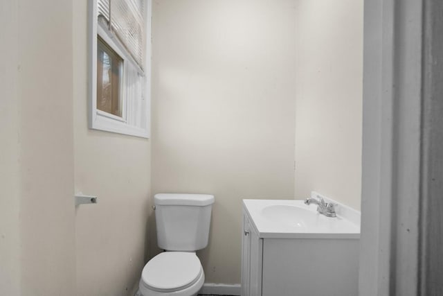 bathroom with toilet, vanity, and baseboards