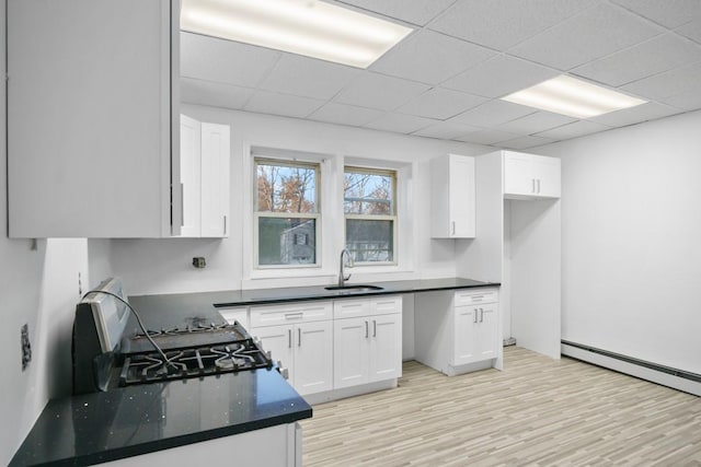 kitchen with light wood finished floors, a sink, and white cabinets