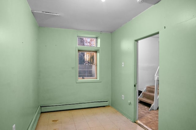 empty room with stairway, baseboard heating, and tile patterned floors