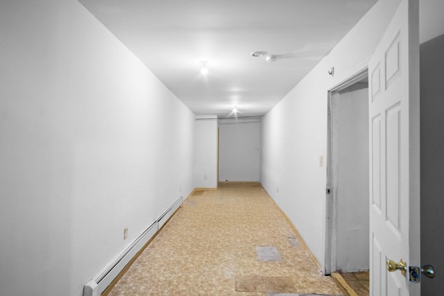 hallway with a baseboard heating unit, light floors, and baseboards