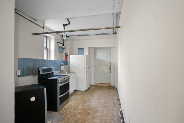 kitchen with white cabinets, range with two ovens, freestanding refrigerator, a baseboard heating unit, and a sink