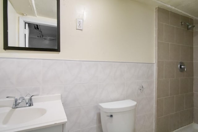 bathroom featuring tile walls, a tile shower, vanity, and toilet