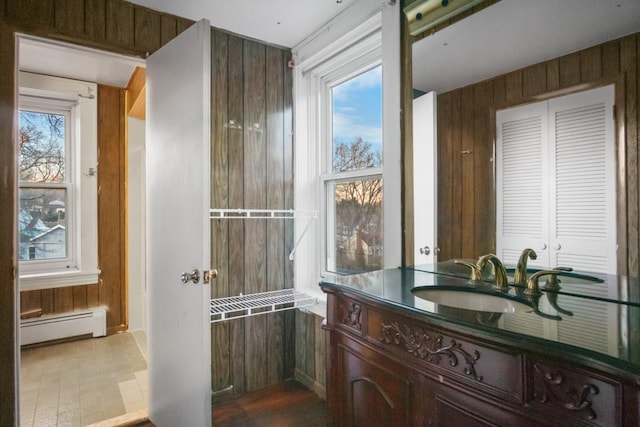 bathroom featuring baseboard heating, vanity, and wooden walls