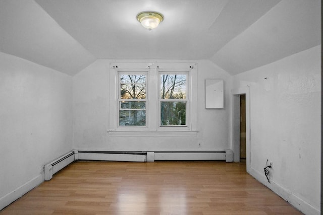 additional living space featuring vaulted ceiling, a baseboard heating unit, and light wood-style flooring