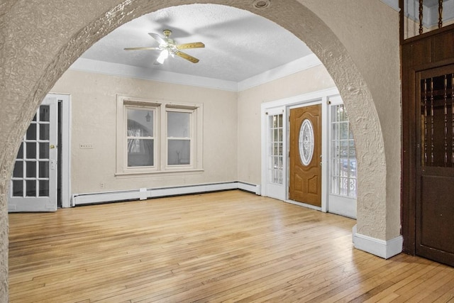 entrance foyer with arched walkways, a textured wall, a baseboard heating unit, a ceiling fan, and hardwood / wood-style floors