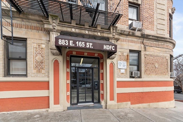 view of exterior entry featuring brick siding and cooling unit