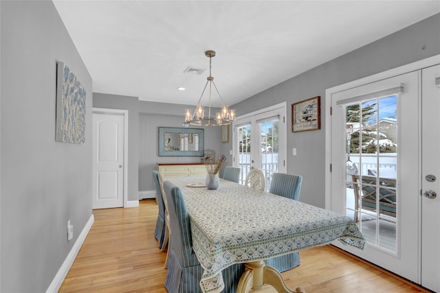 dining space featuring french doors, light wood-style flooring, visible vents, and baseboards