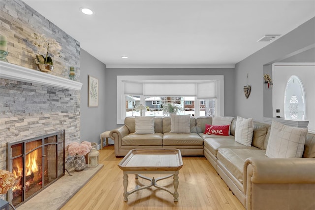 living area featuring recessed lighting, visible vents, a stone fireplace, and light wood finished floors