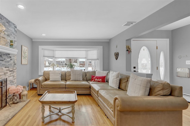 living room with visible vents, a stone fireplace, and light wood finished floors