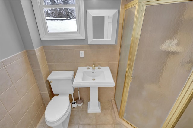 bathroom with toilet, a stall shower, tile walls, and tile patterned floors