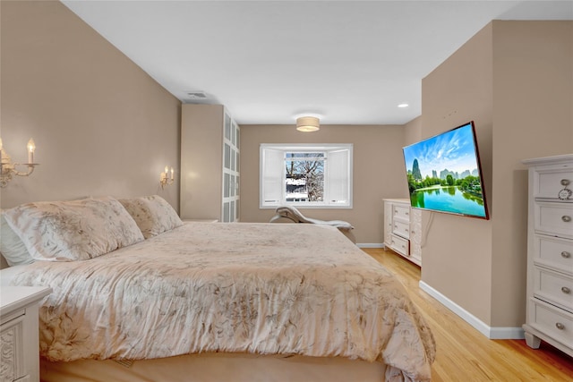 bedroom featuring light wood-type flooring, visible vents, and baseboards