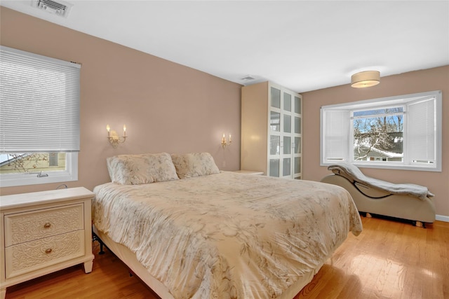 bedroom with visible vents, light wood-style flooring, and multiple windows