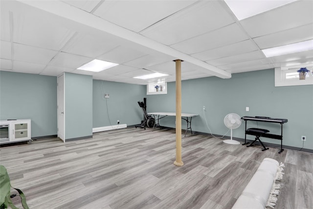 basement featuring a drop ceiling, baseboards, and wood finished floors