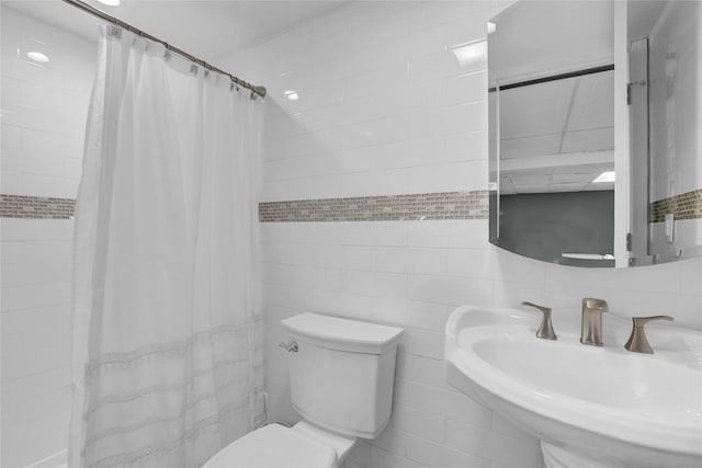 full bathroom featuring toilet, curtained shower, a sink, and tile walls