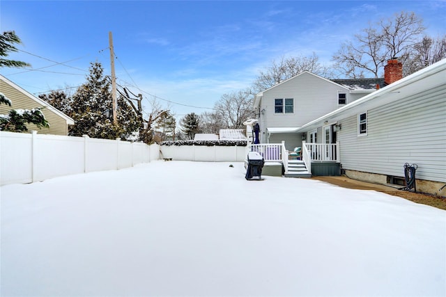 snowy yard with fence and a deck