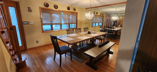 dining space with baseboards, wood-type flooring, and a notable chandelier