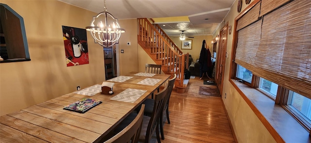 unfurnished dining area with wood-type flooring, stairway, arched walkways, and ceiling fan with notable chandelier