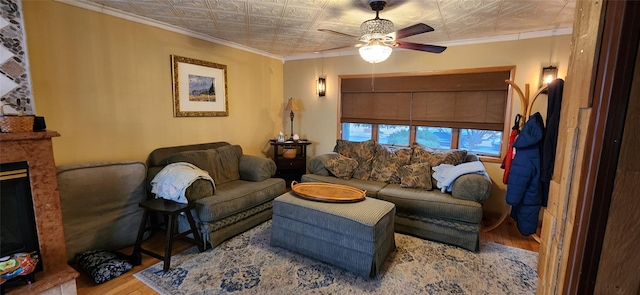 living area with an ornate ceiling, a fireplace, ornamental molding, and wood finished floors