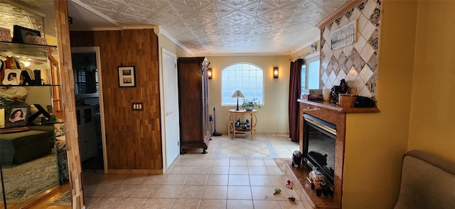 hall featuring an ornate ceiling, crown molding, light tile patterned flooring, wooden walls, and baseboards