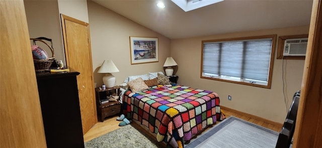 bedroom with baseboards, vaulted ceiling with skylight, and light wood-style floors