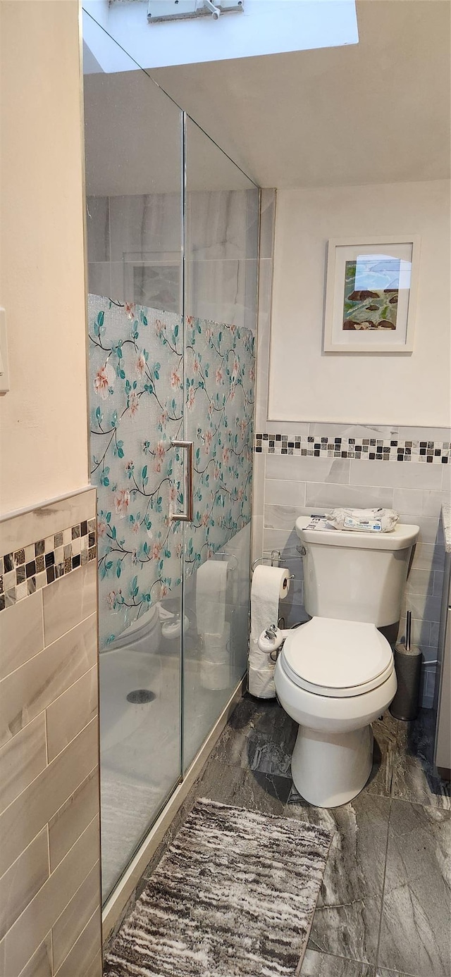 full bathroom featuring toilet, a stall shower, and tile walls