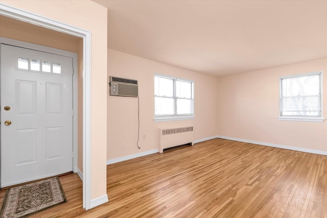 foyer entrance with plenty of natural light, radiator heating unit, a wall mounted air conditioner, and light wood-style floors