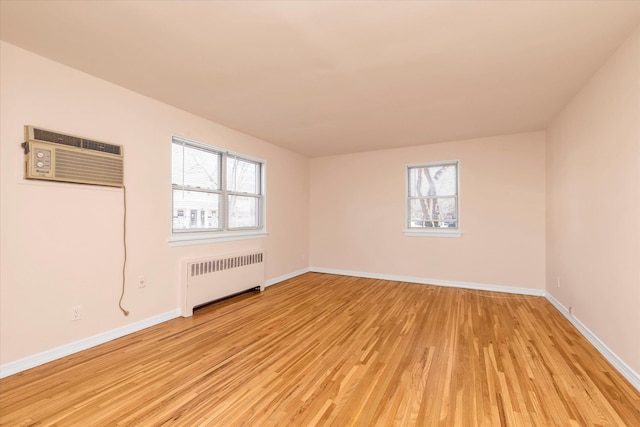 spare room featuring light wood-type flooring, a wealth of natural light, baseboards, and radiator heating unit