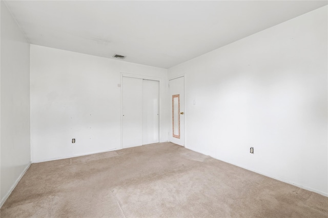 spare room featuring visible vents and light colored carpet