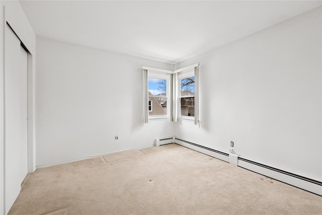 unfurnished bedroom featuring light carpet, a baseboard heating unit, and a closet