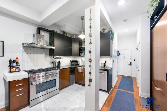 kitchen with decorative backsplash, appliances with stainless steel finishes, pendant lighting, wall chimney range hood, and open shelves