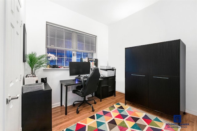 home office featuring baseboards and light wood finished floors