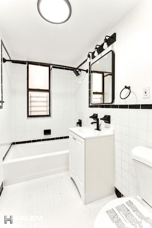 bathroom featuring toilet, shower / tub combination, tile patterned floors, vanity, and tile walls