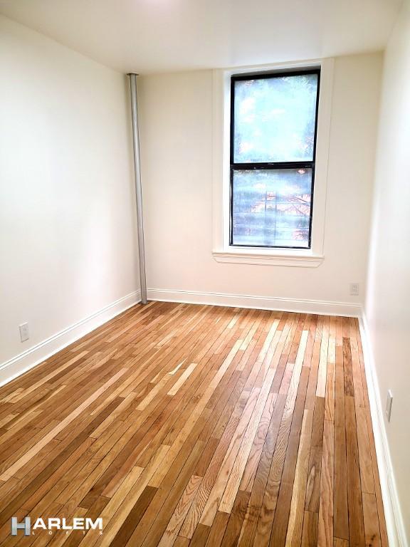 empty room with baseboards and hardwood / wood-style flooring