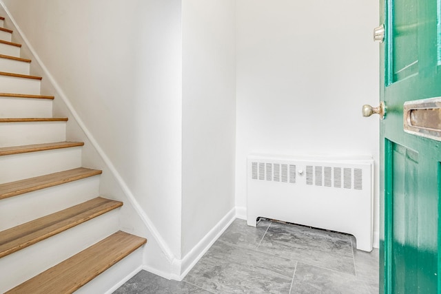 entrance foyer with stairway, radiator heating unit, and baseboards