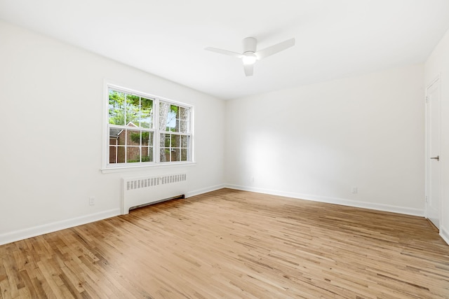 unfurnished room with radiator, a ceiling fan, baseboards, and wood finished floors