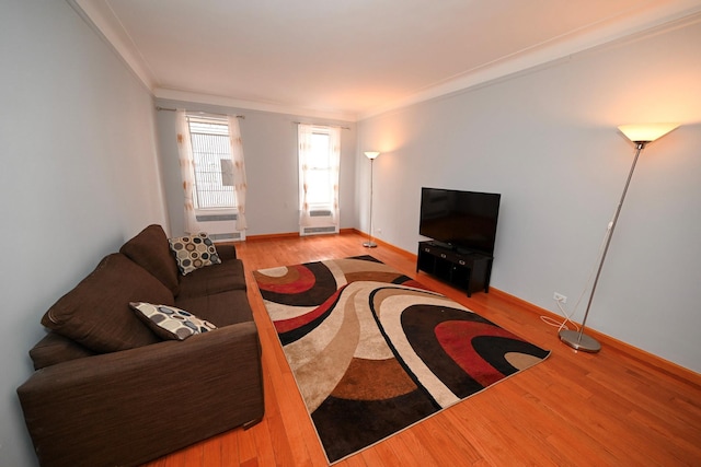 living room featuring baseboards, ornamental molding, and wood finished floors