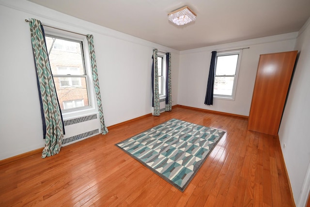 unfurnished room featuring light wood-style floors, radiator heating unit, and baseboards