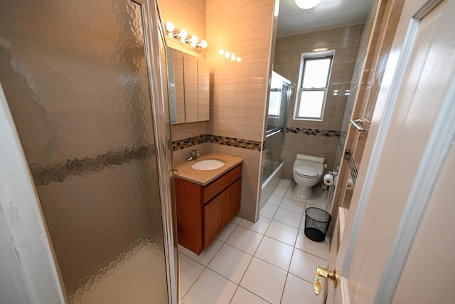 full bathroom with tile walls, vanity, toilet, and tile patterned floors